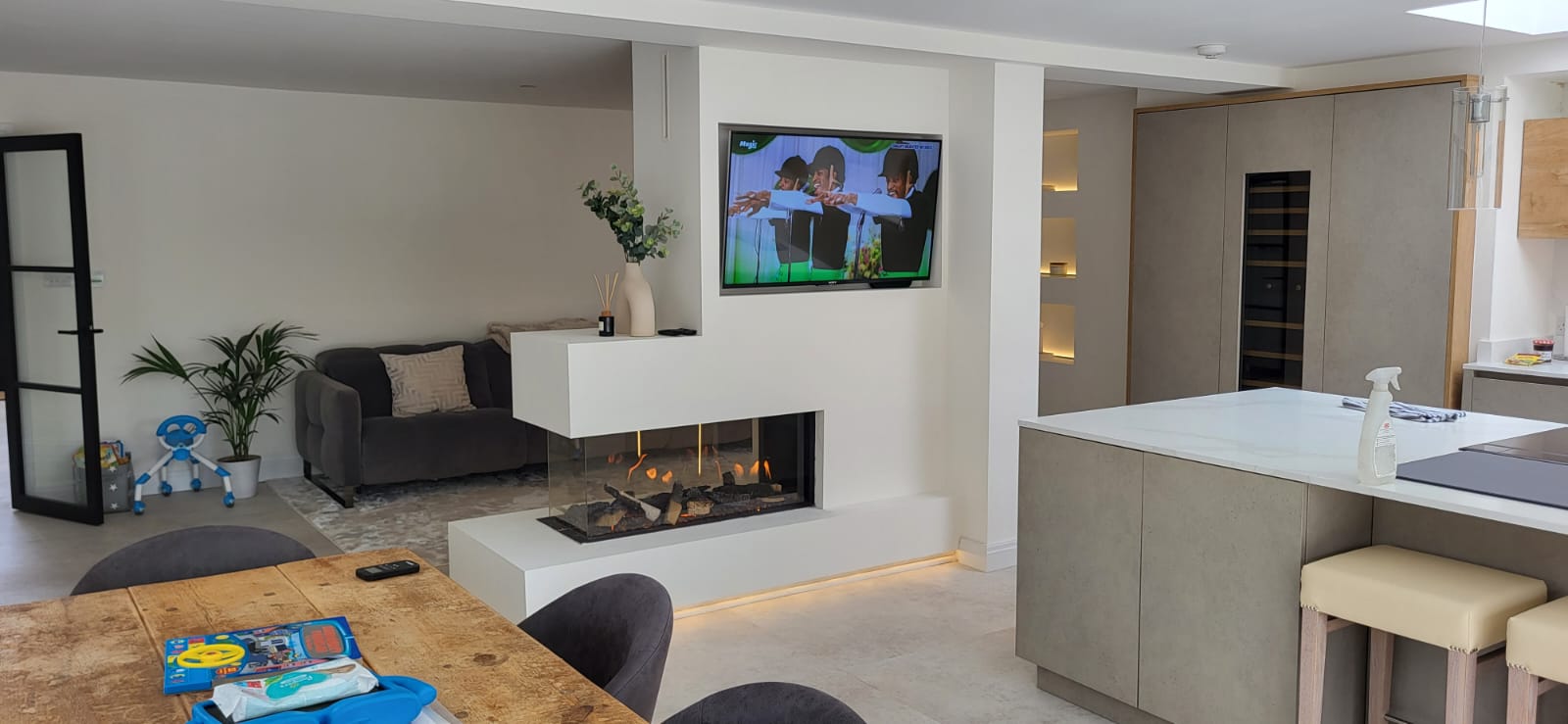 White fireplace and television feature dividing an open-plan living space